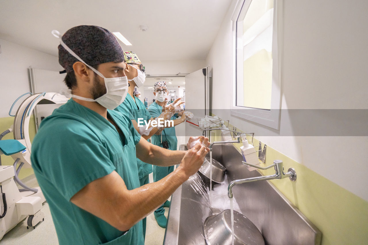 Doctors wearing masks washing hands in hospital