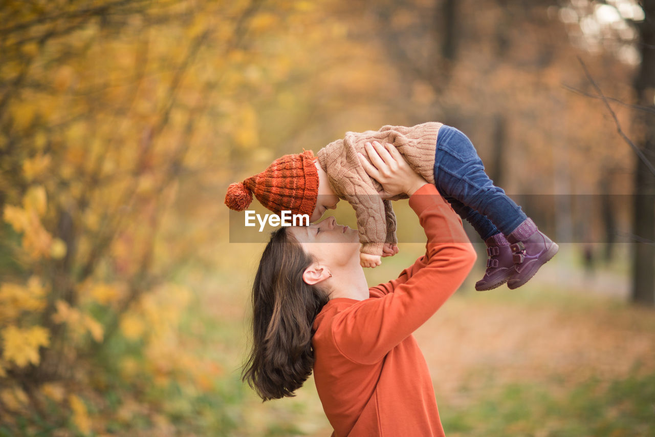 Mother with child in her arms against background of autumn. family mom and baby walk in park. 