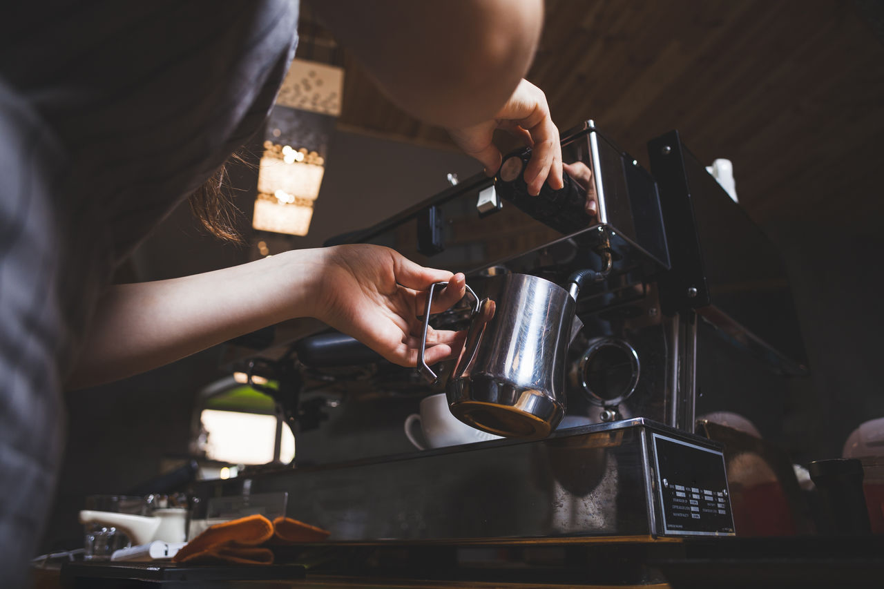 Midsection of barista filling coffee in mug