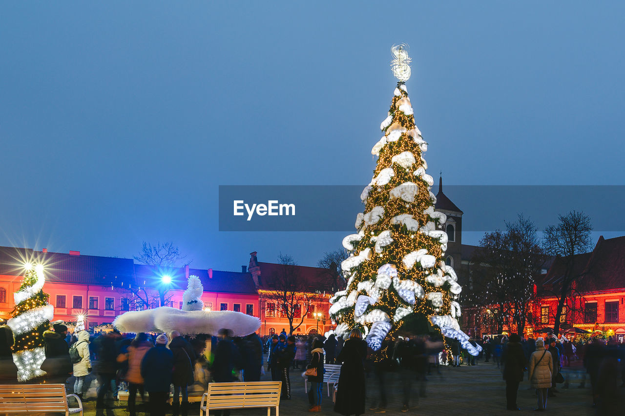 PEOPLE ON ILLUMINATED CHRISTMAS TREE AT NIGHT