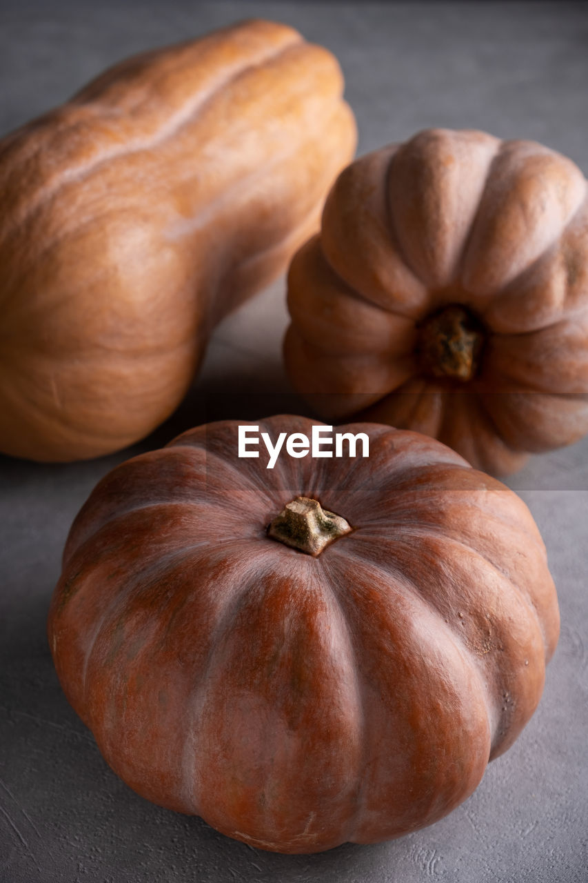 Three ripe pumpkins on a gray background. vertical orientation. selective focus.