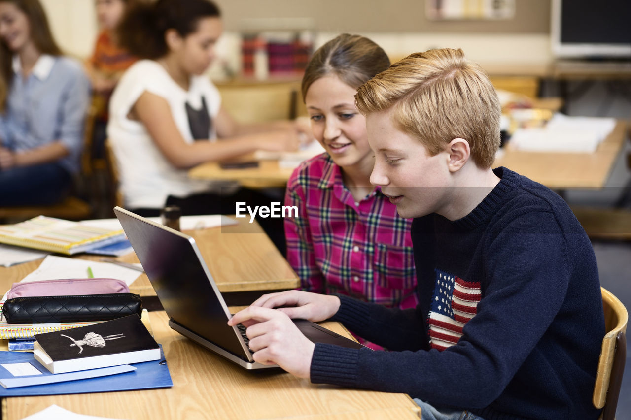 School students using laptop in classroom