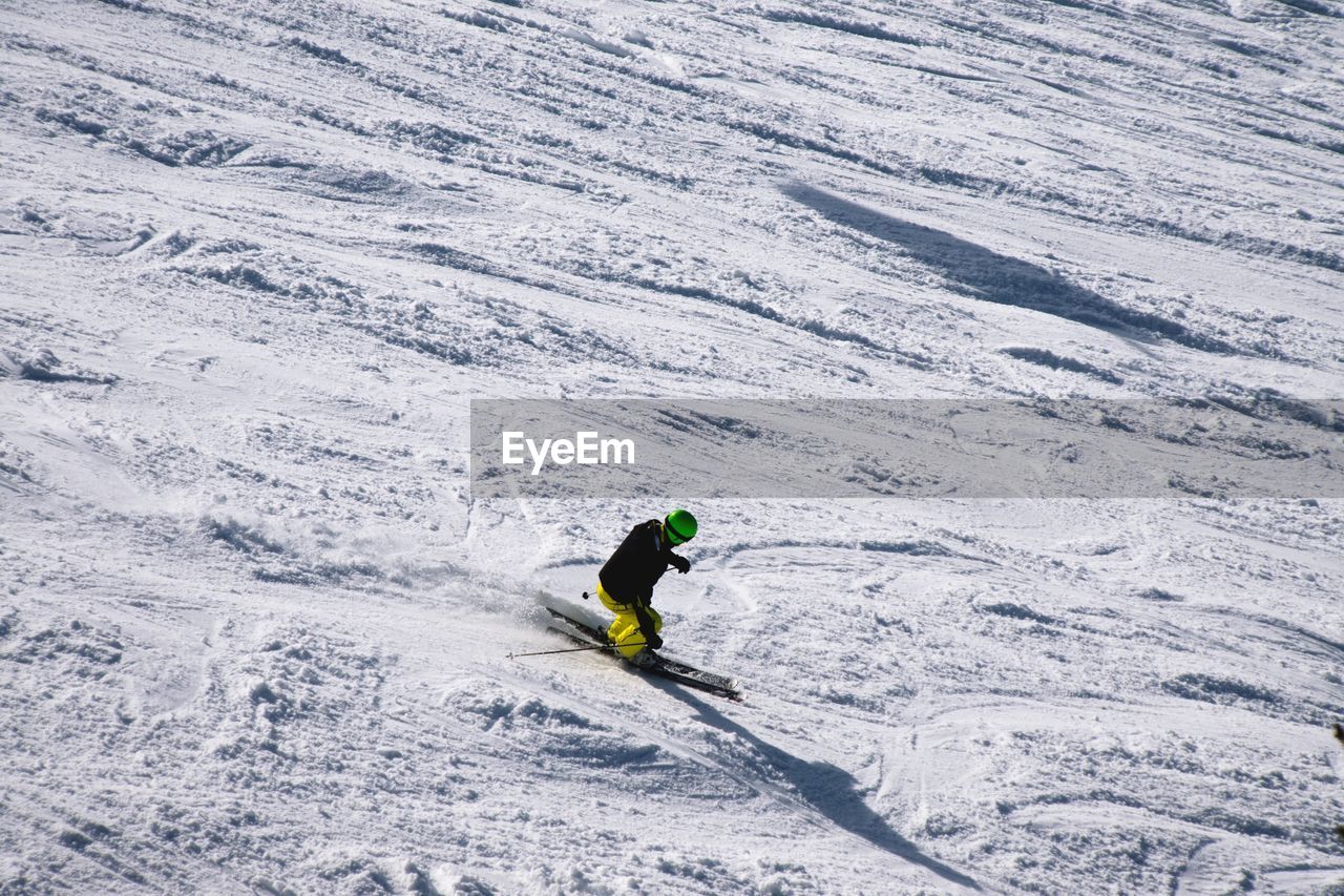 HIGH ANGLE VIEW OF PERSON SKIING ON SNOWY FIELD