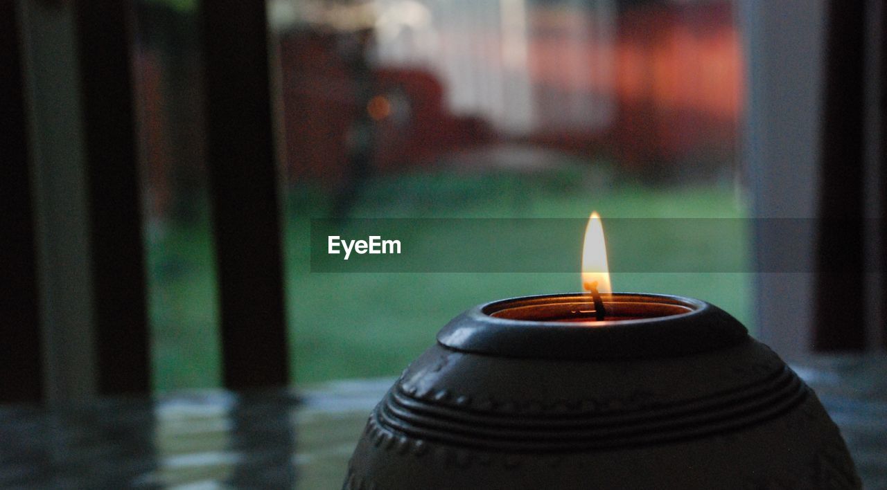 CLOSE-UP OF ILLUMINATED TEA LIGHT CANDLES ON TABLE