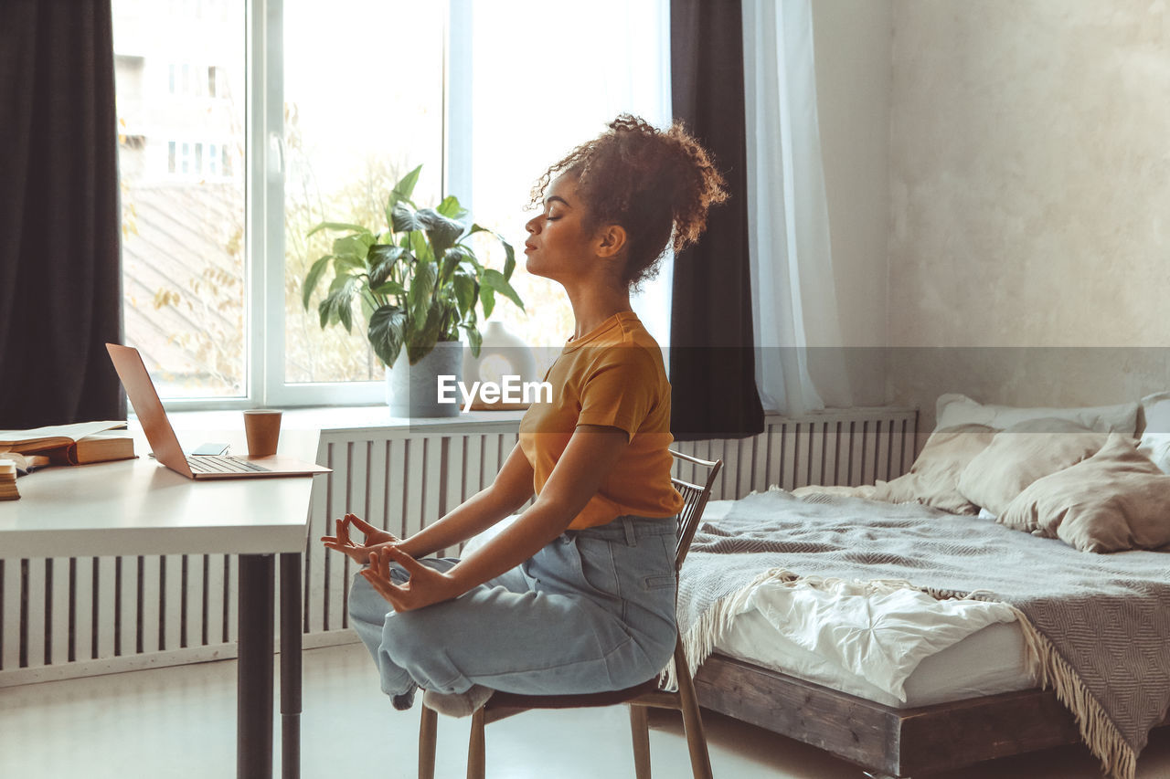 Side view of girl meditating at home