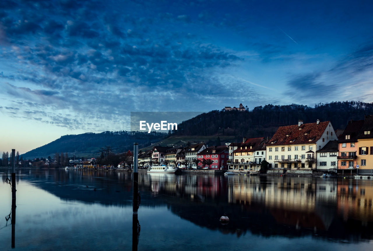 Scenic view of lake and buildings against sky at dusk