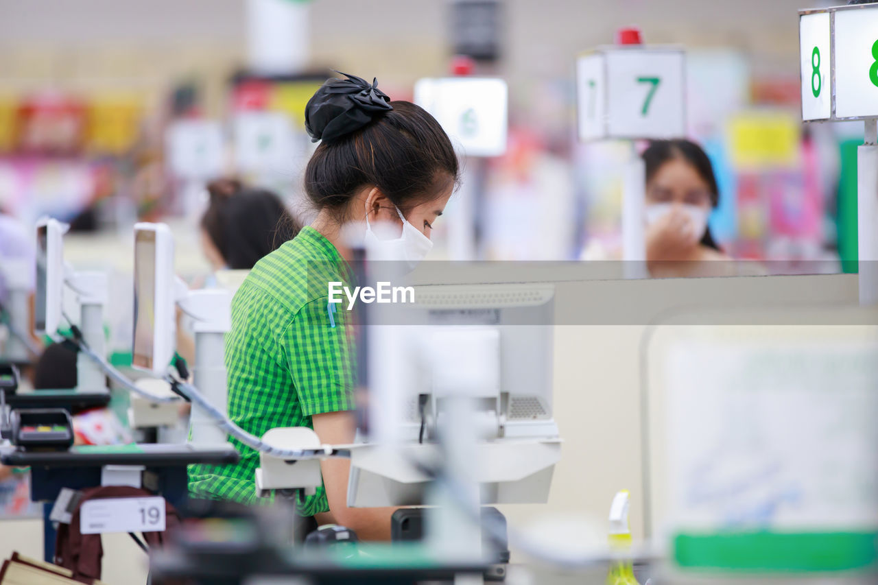 Side view of woman wearing mask working in store