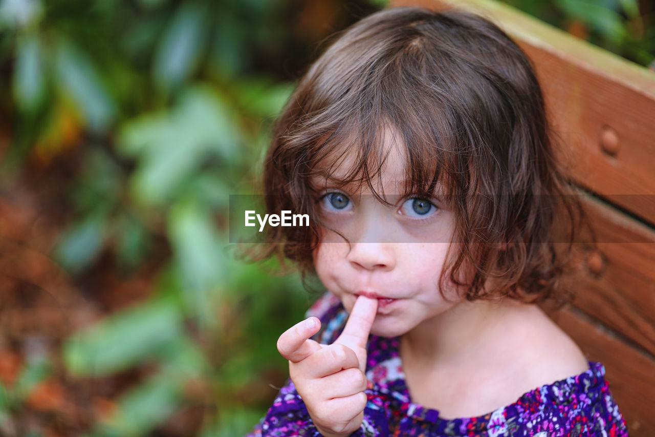 Portrait of cute girl sucking thumb outdoors