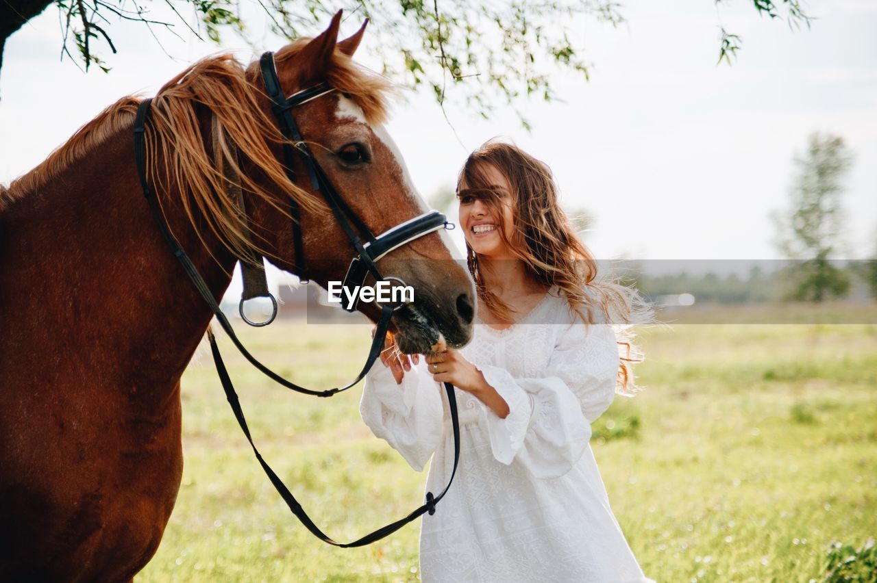 Smiling woman with horse standing on field