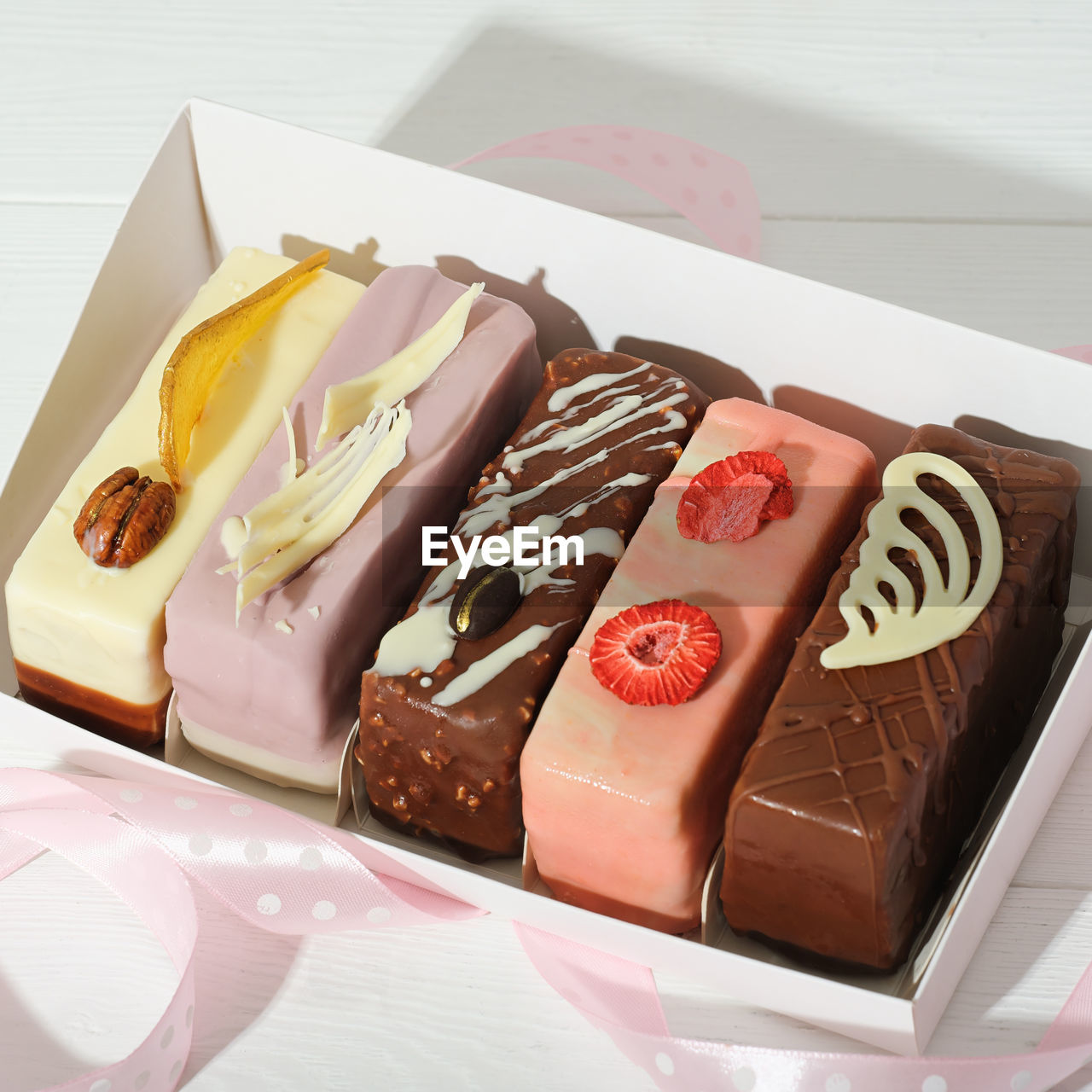 Set of various mini cakes in a box with festive decor unboxed. glazed with chocolate
 and icing 