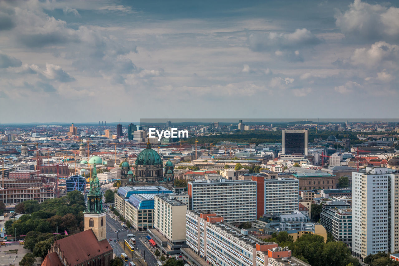 High angle view of city buildings against cloudy sky