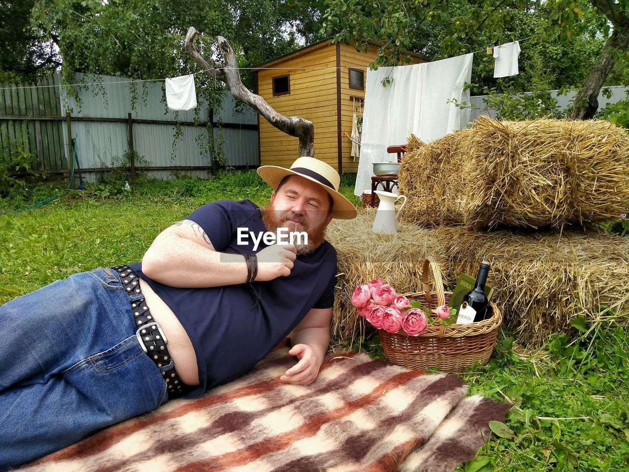 PORTRAIT OF SMILING MAN SITTING BY FLOWER PLANT