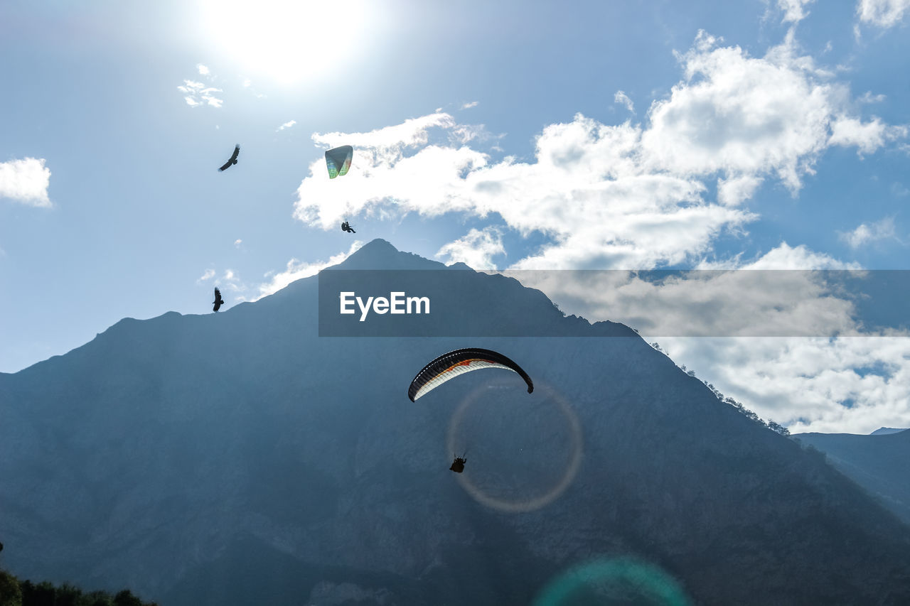 Person paragliding over mountain against sky