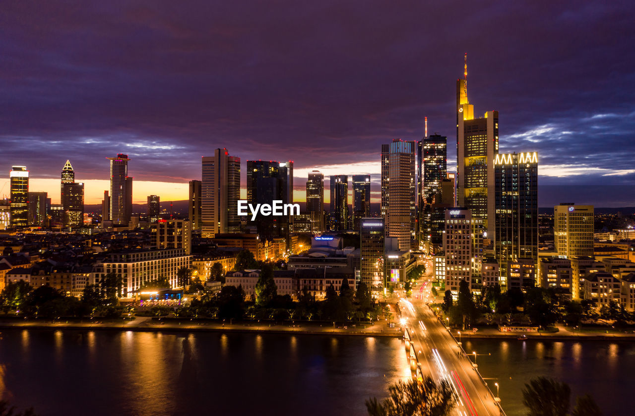 Wide view of frankfurt am main skyline at night with main river in foreground and city lights