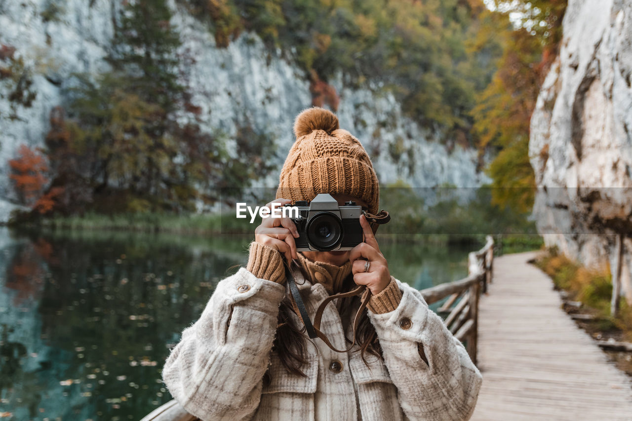 Portrait of young woman taking photos of beautiful autumn nature with a vintage film camera