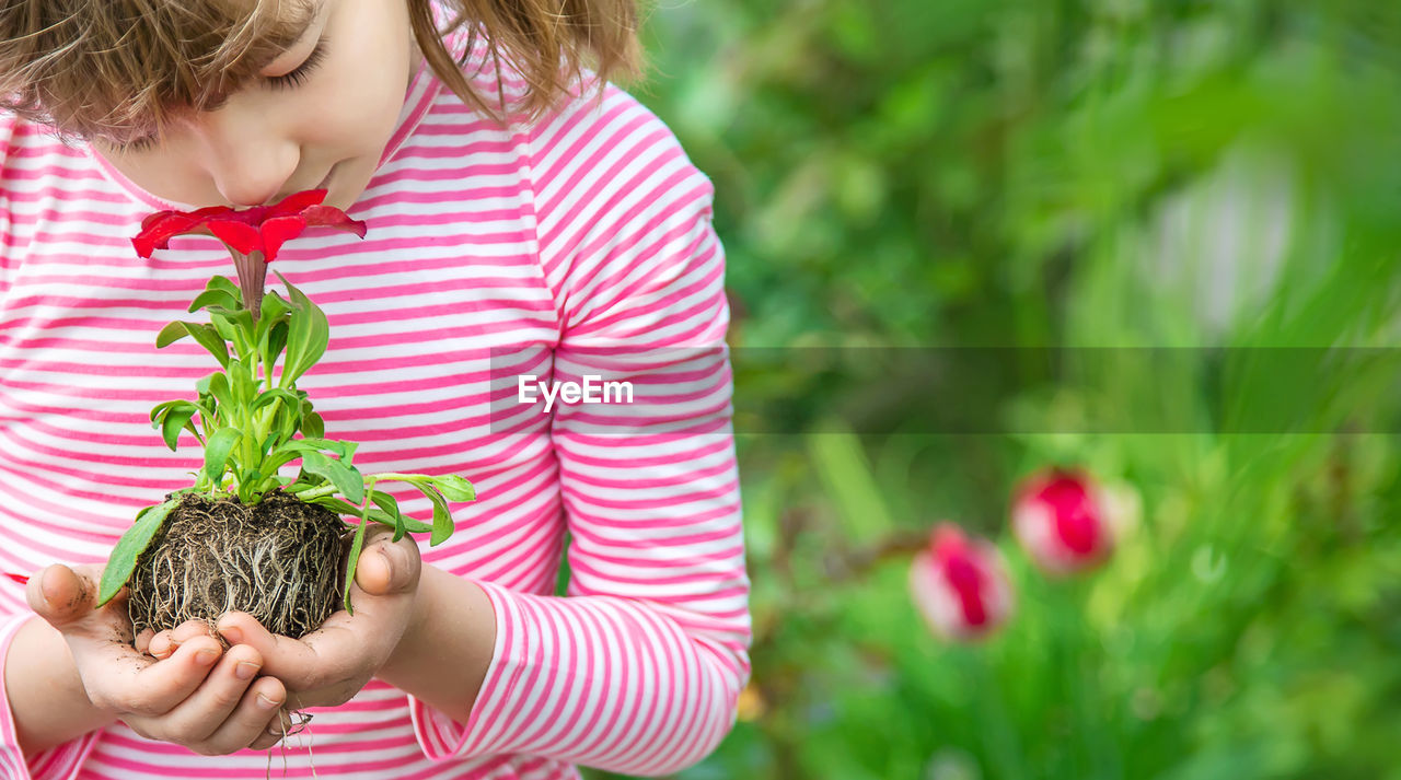 Girl with eyes closed smelling flower