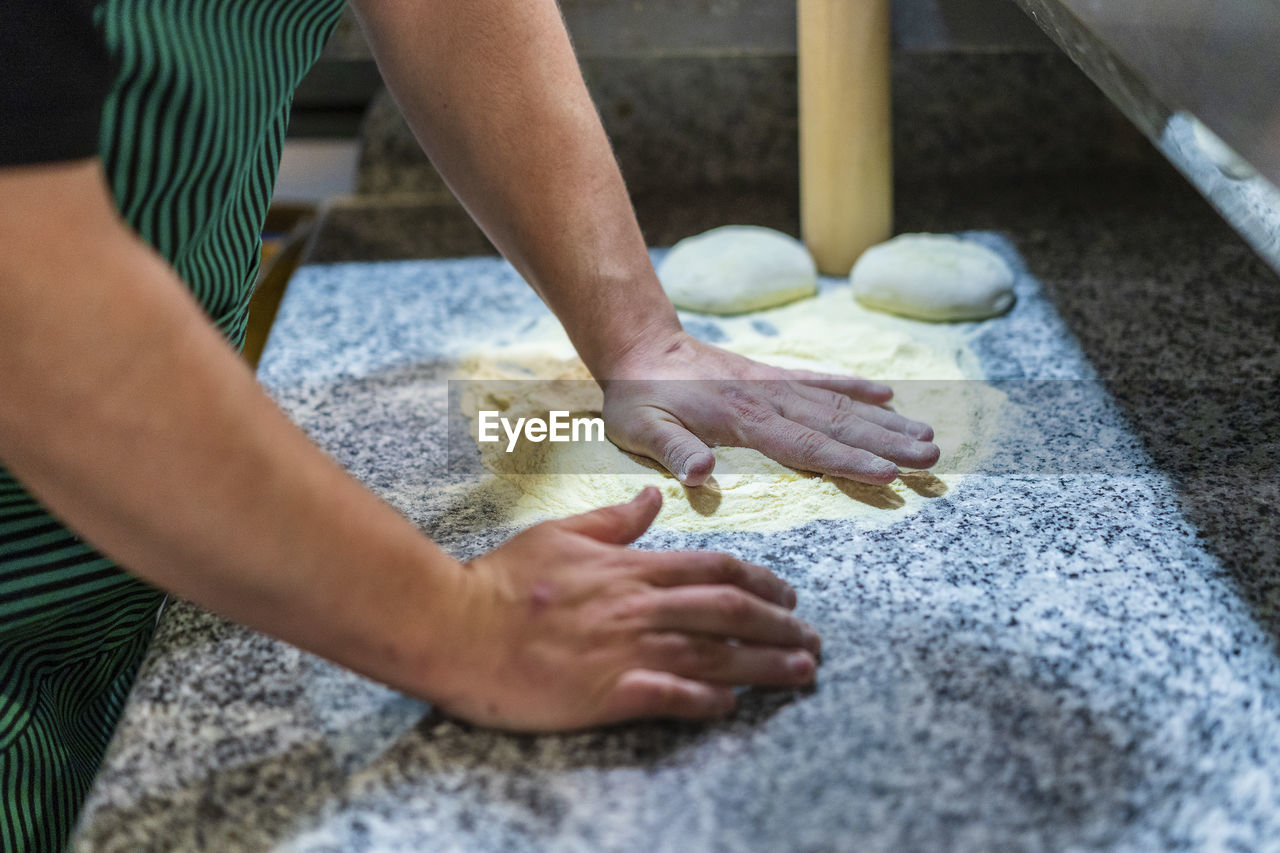Arms of chef preparing pizza dough