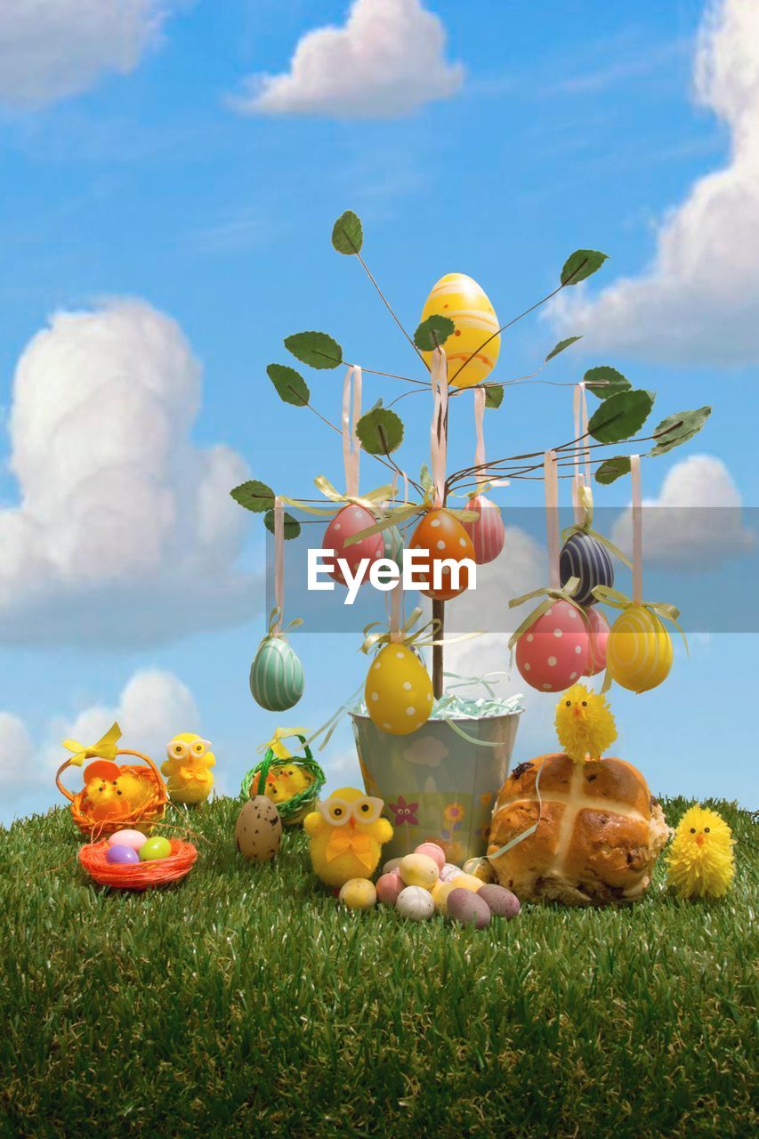 Toys and easter eggs on grassy field against sky