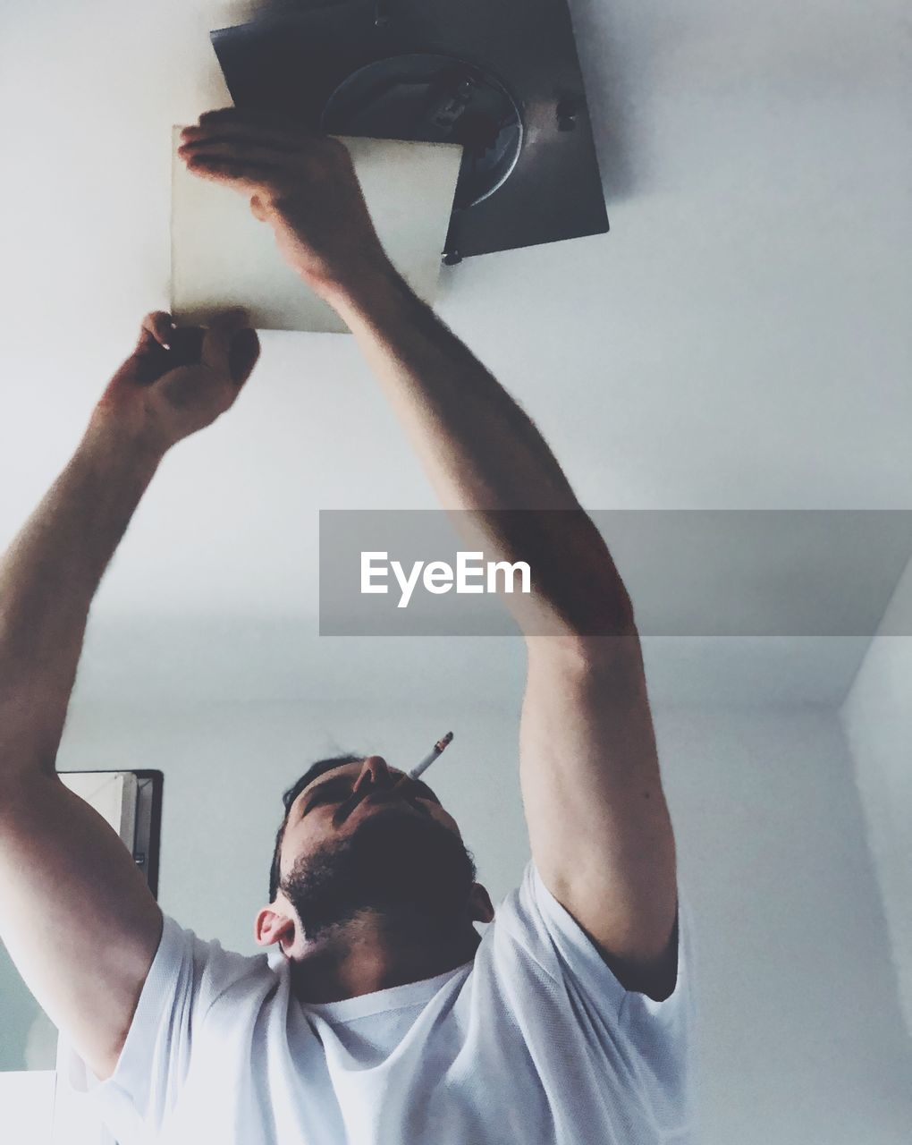 Man smoking cigarette while opening ceiling