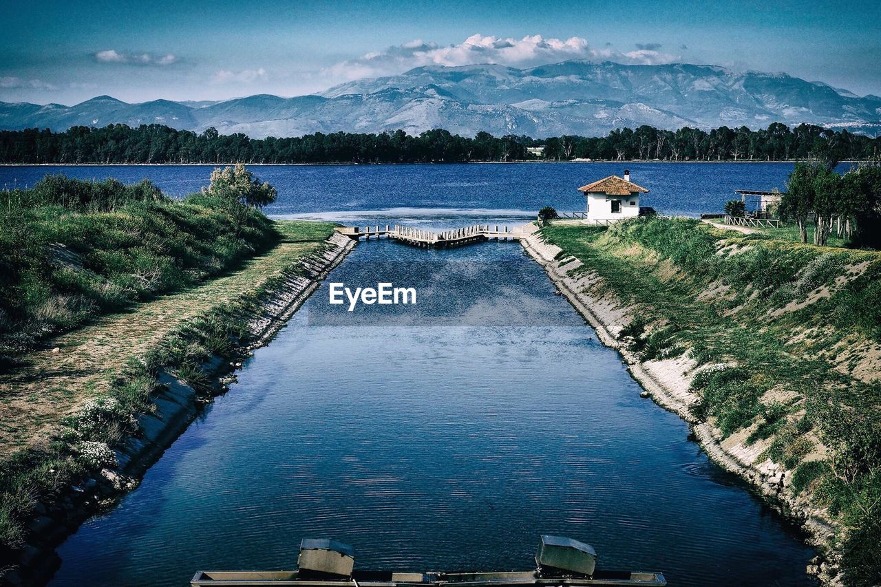 River with trees and mountains against cloudy sky