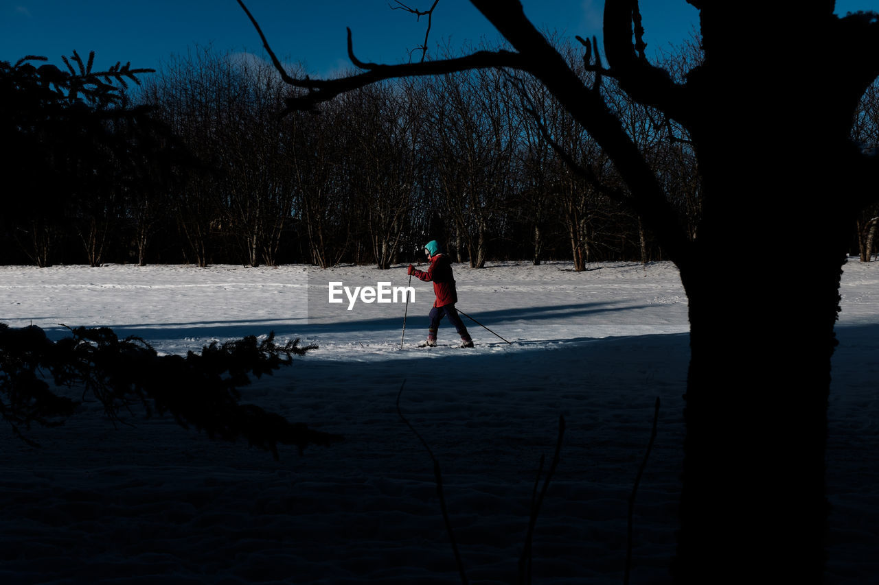 MAN STANDING ON FROZEN LAKE AGAINST SKY