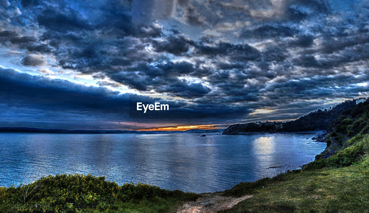 SCENIC VIEW OF CALM LAKE AGAINST CLOUDY SKY