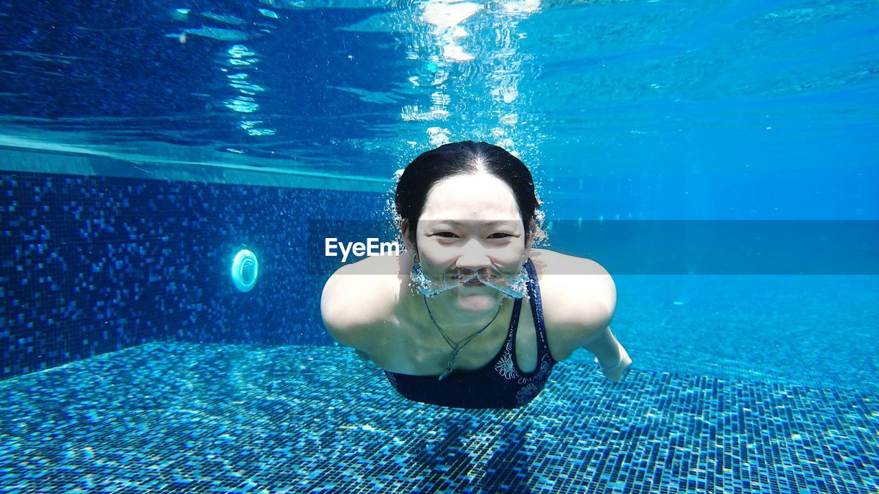 Portrait of young woman swimming underwater in pool