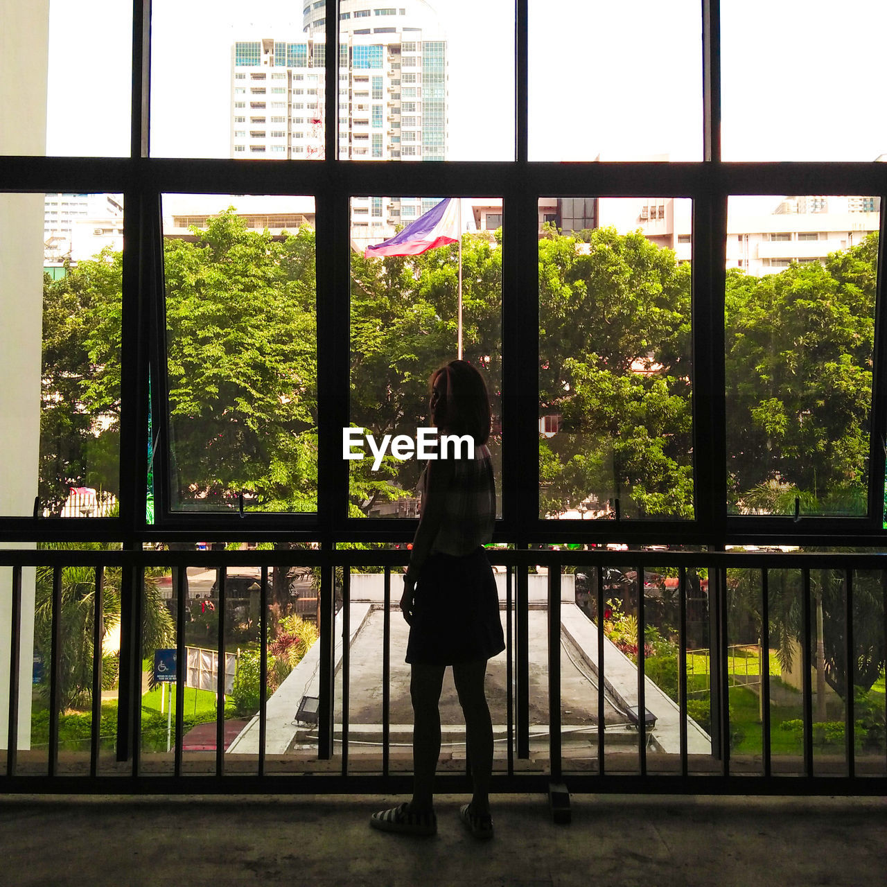 FULL LENGTH OF WOMAN STANDING BY WINDOW