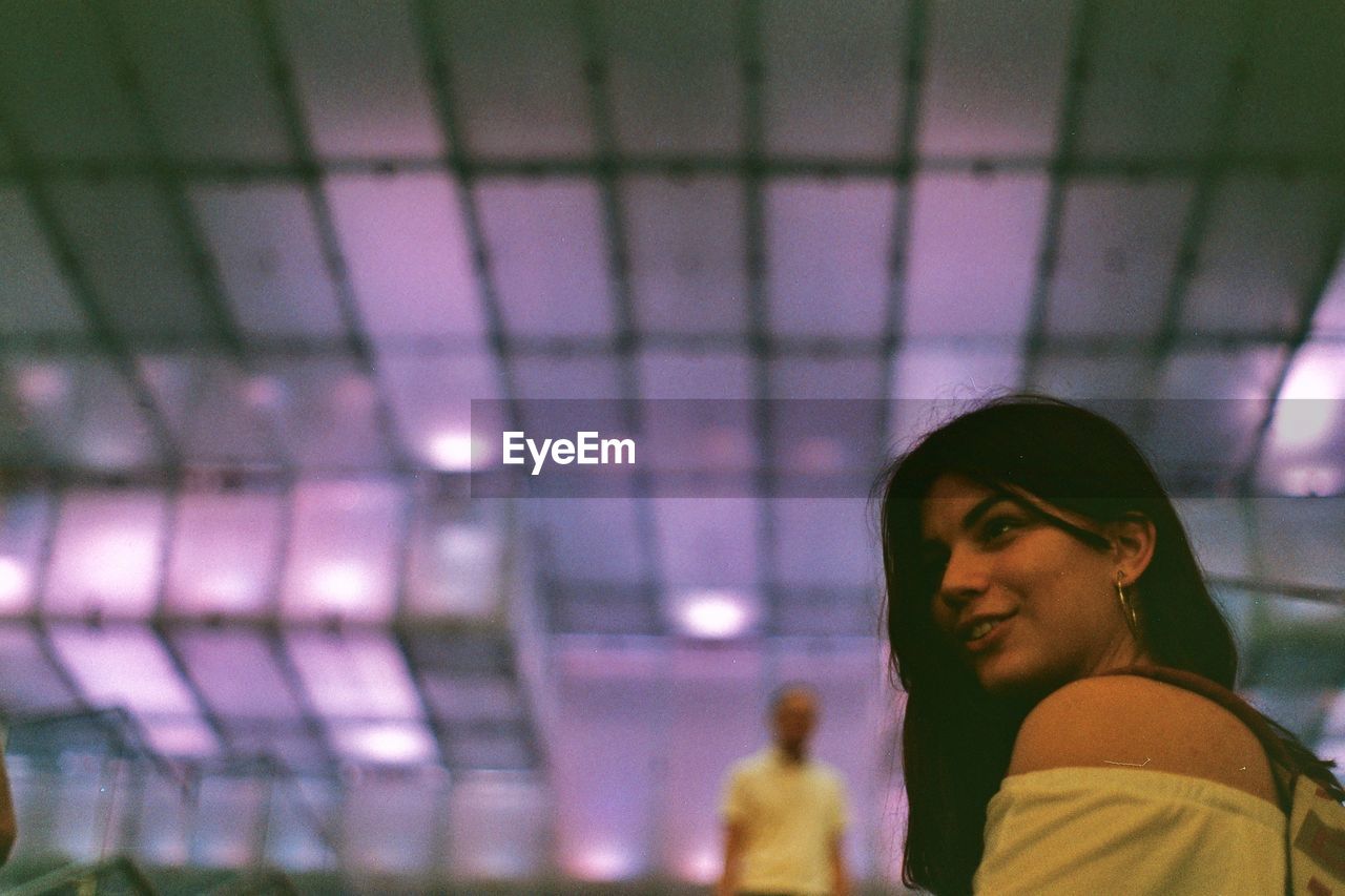 Close-up of smiling woman against ceiling