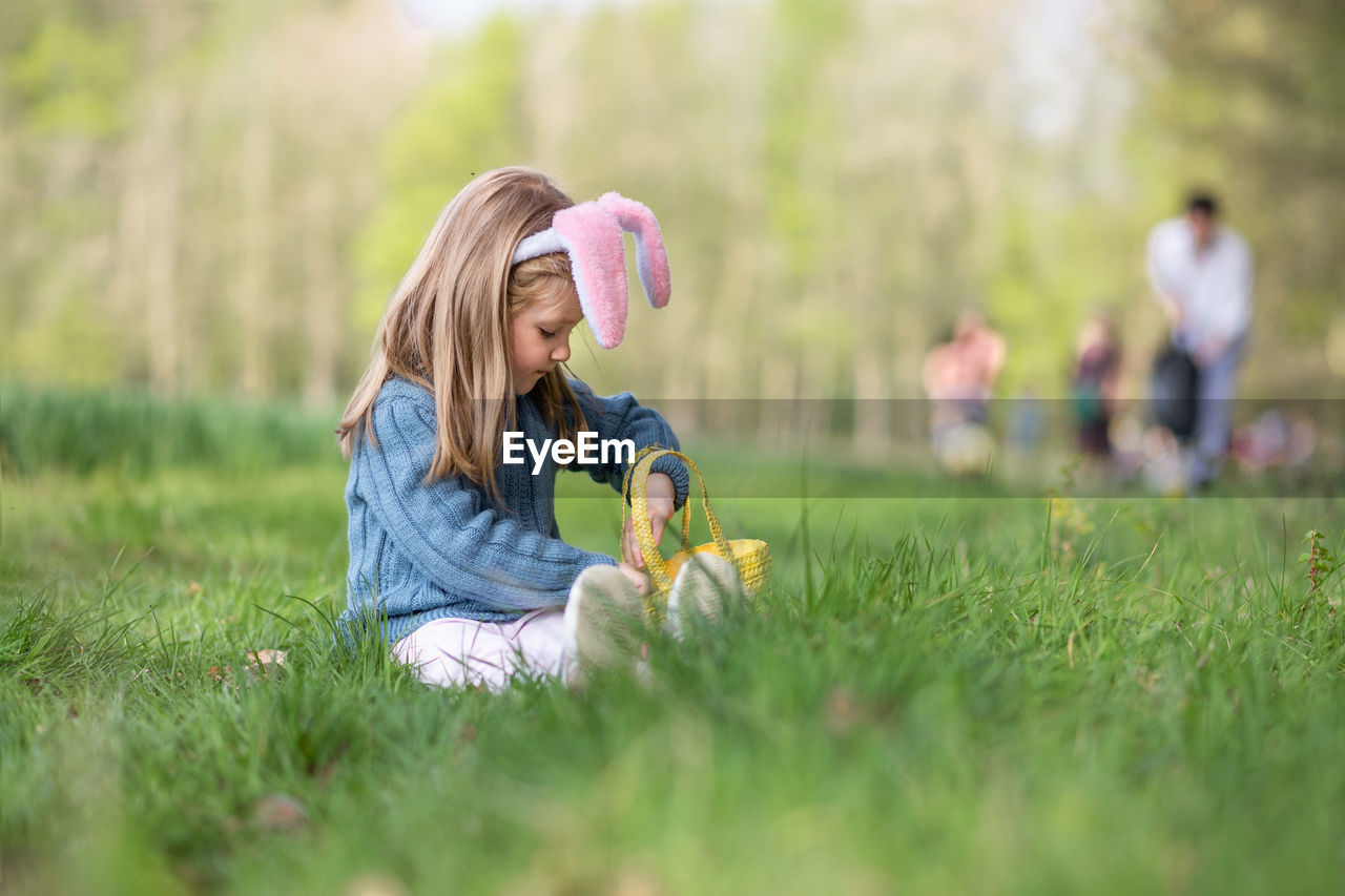 Girl with bunny ears collects the eggs for easter