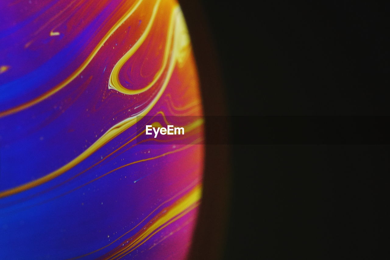 Close-up of multi colored soap bubble against black background