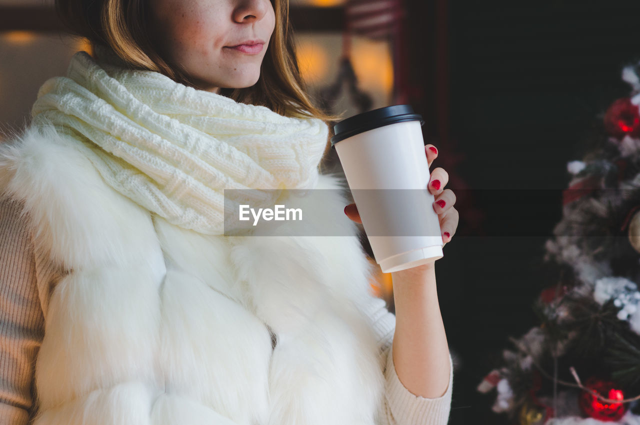 Midsection of woman having coffee during christmas