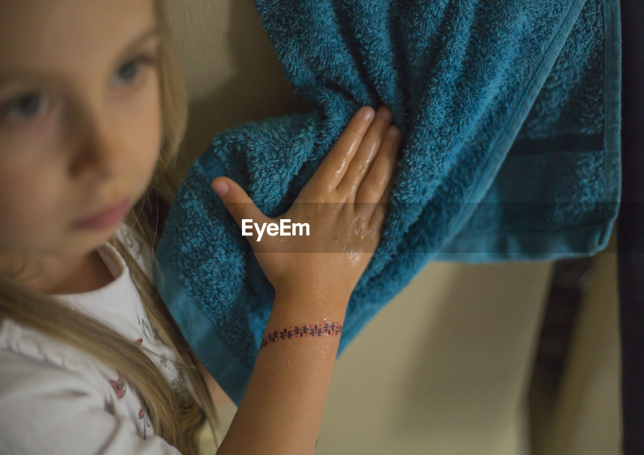 Close-up of girl drying hands by using towel at home