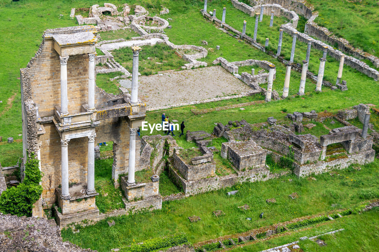 Tourists group visiting remains or ruin of ancient roman amphitheatre in volterra, tuscany, italy