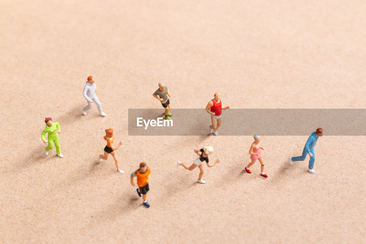 Miniature people exercising while running in a group on the beach