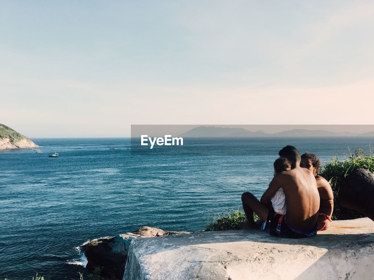 PEOPLE SITTING ON SEA AGAINST SKY