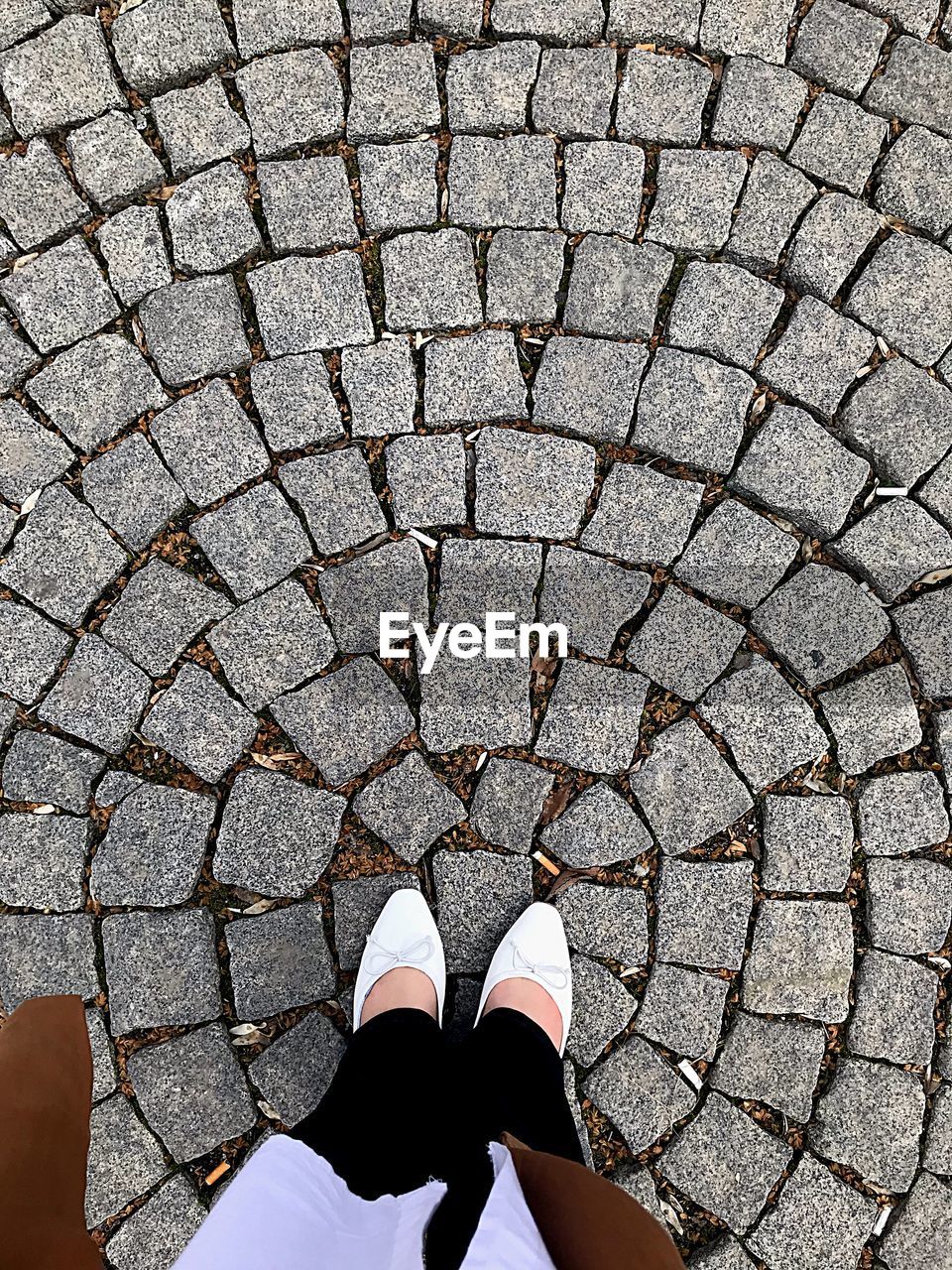 Low section of woman standing on cobblestone street