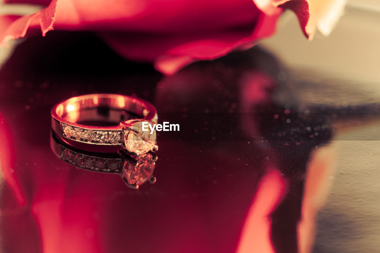 CLOSE-UP OF WEDDING RINGS ON RED FLOWER