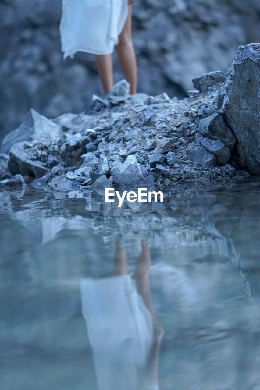 Low section of woman reflecting in lake