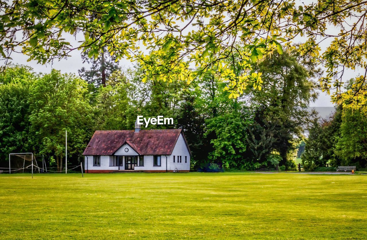 HOUSE AND TREES ON FIELD AGAINST SKY