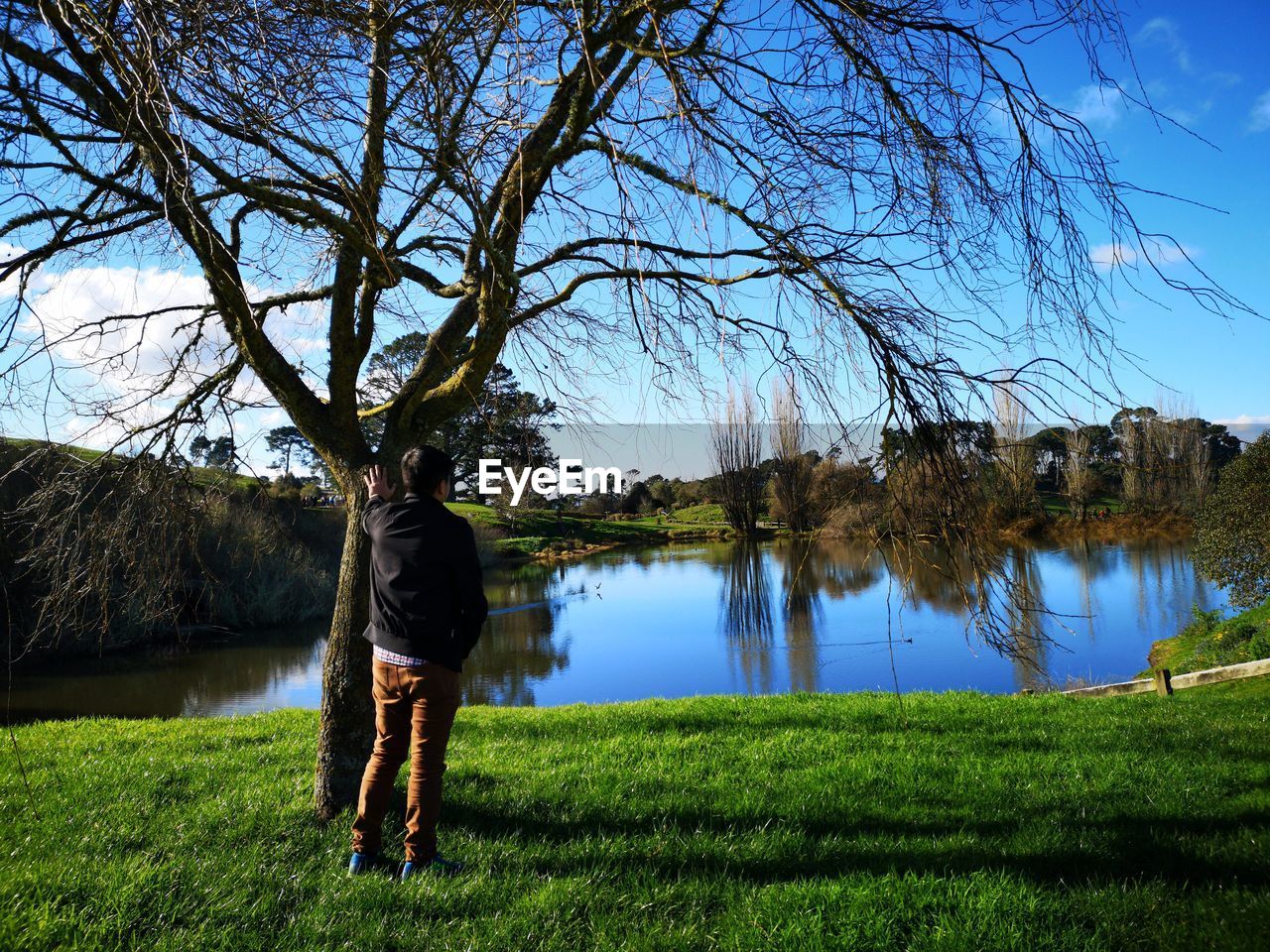 Rear view of man standing by lake against sky