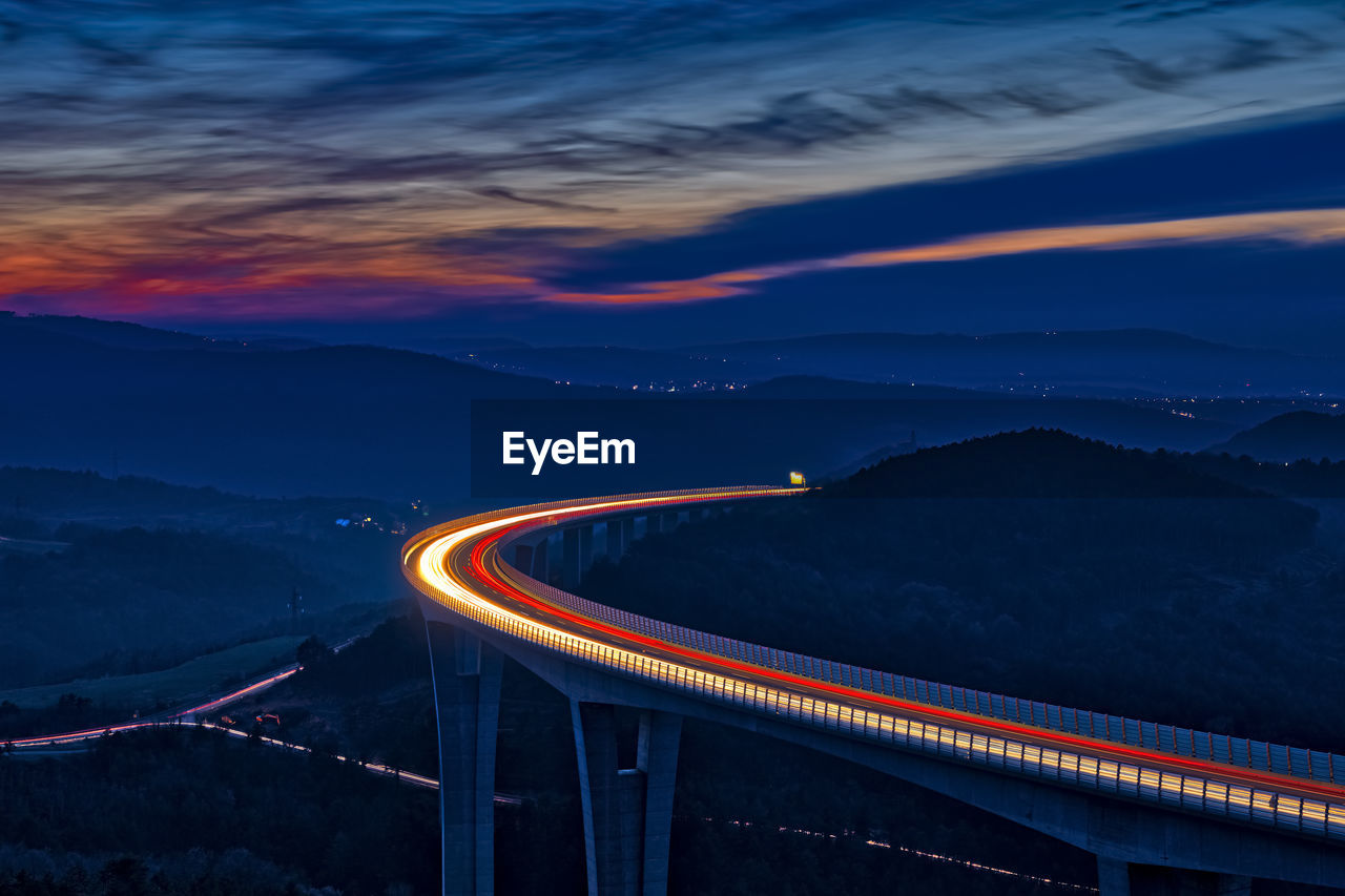 Light trails on road against sky at night