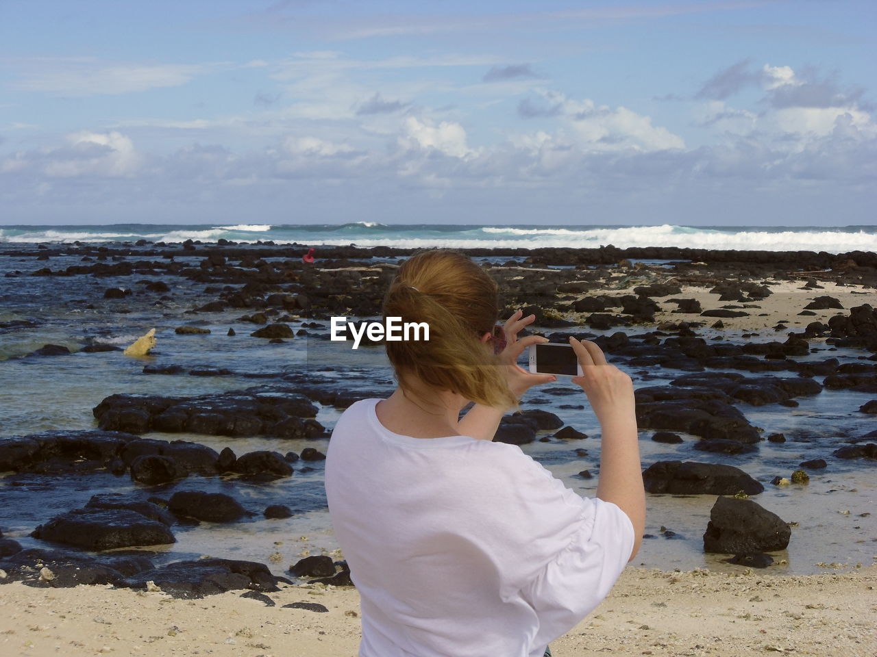 Rear view of woman photographing sea against sky