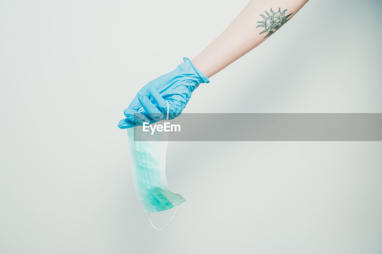 Cropped hand holding mask against white background