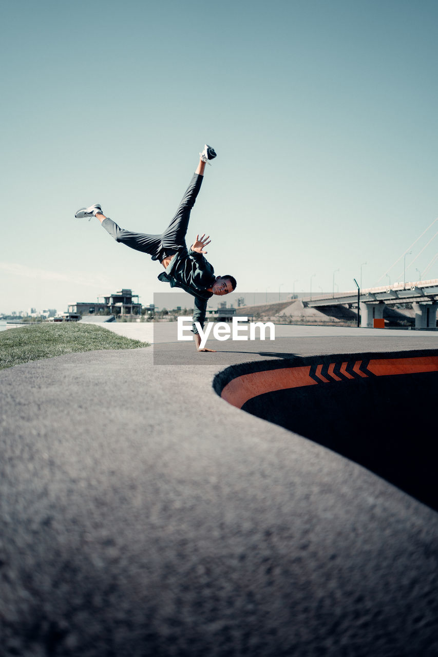 LOW ANGLE VIEW OF MAN JUMPING AT AIRPORT