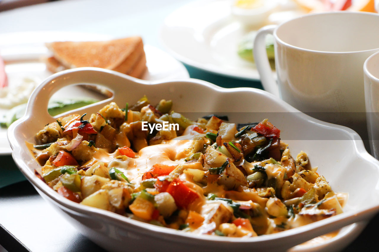 High angle close-up of food served in bowl by coffee cup on table