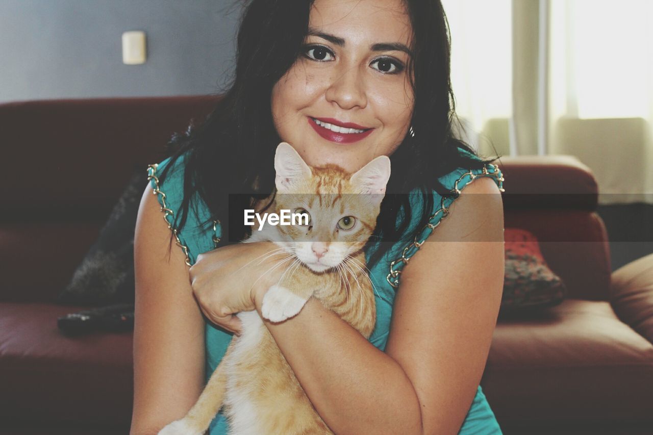 Portrait of smiling woman with cat at home