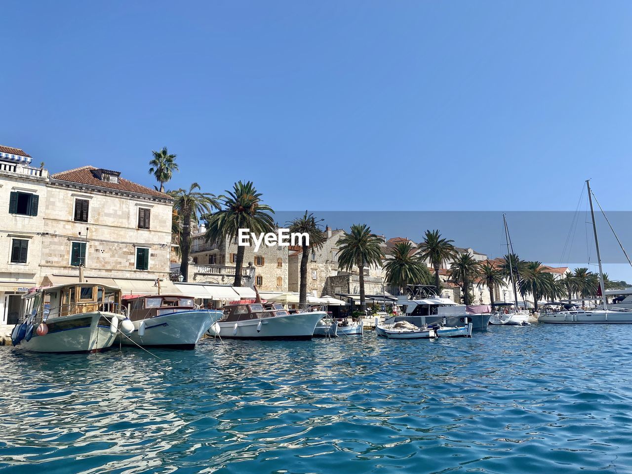 SAILBOATS MOORED ON SEA AGAINST CLEAR BLUE SKY