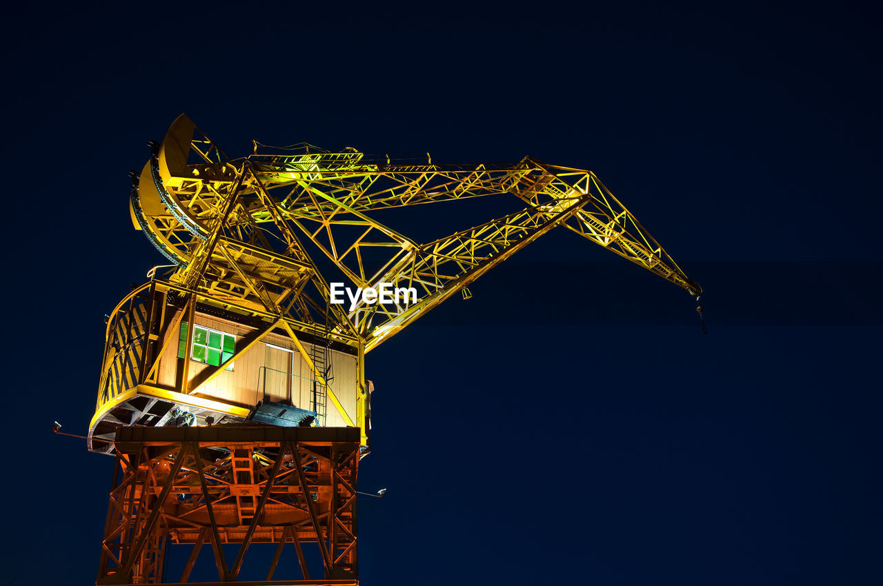 Low angle view of illuminated crane against sky at night