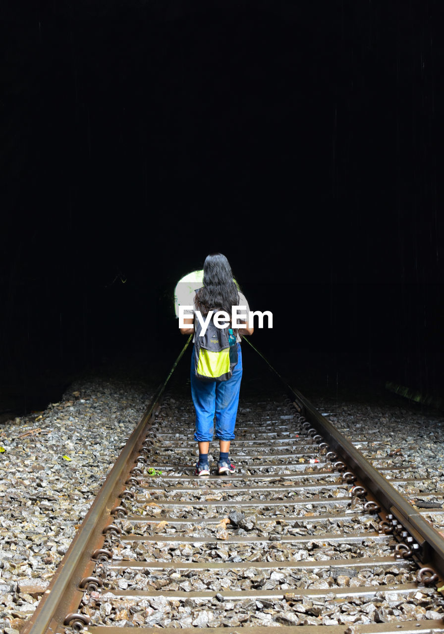 Rear view of woman walking on railroad track